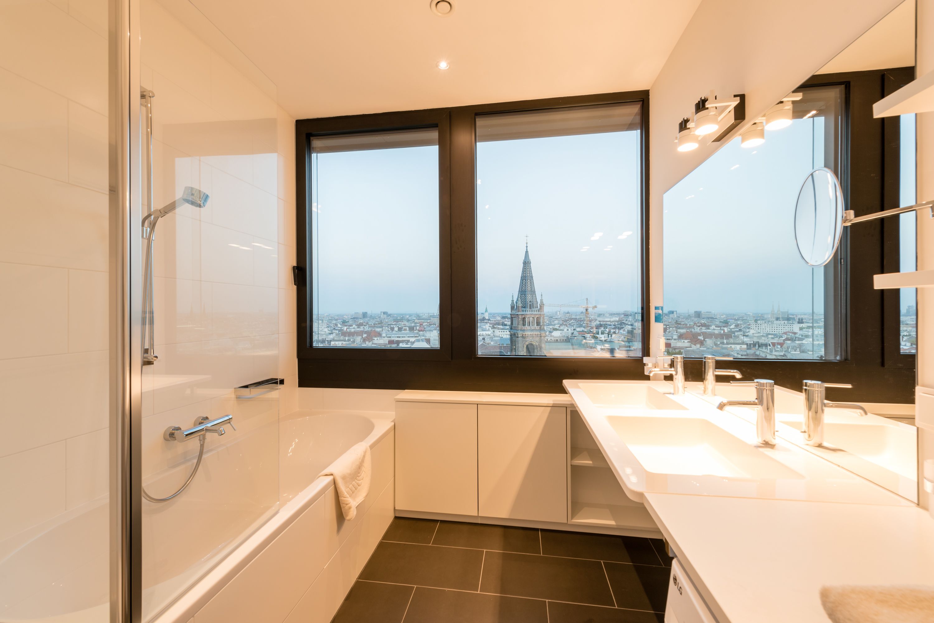 Un baño moderno con un ventanal grande, una bañera, una ducha y un lavabo.