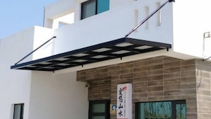 A modern two-story building with a flat roof, large windows, and a covered entrance area. - Ai Lian Shan Shui Homestay (Magong)