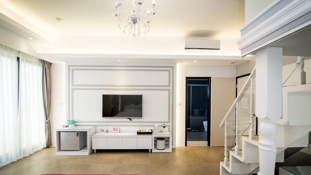 A modern hotel room with a large bed, a flat-screen TV, a small desk, and a staircase. - Ai Lian Shan Shui Homestay (Magong)