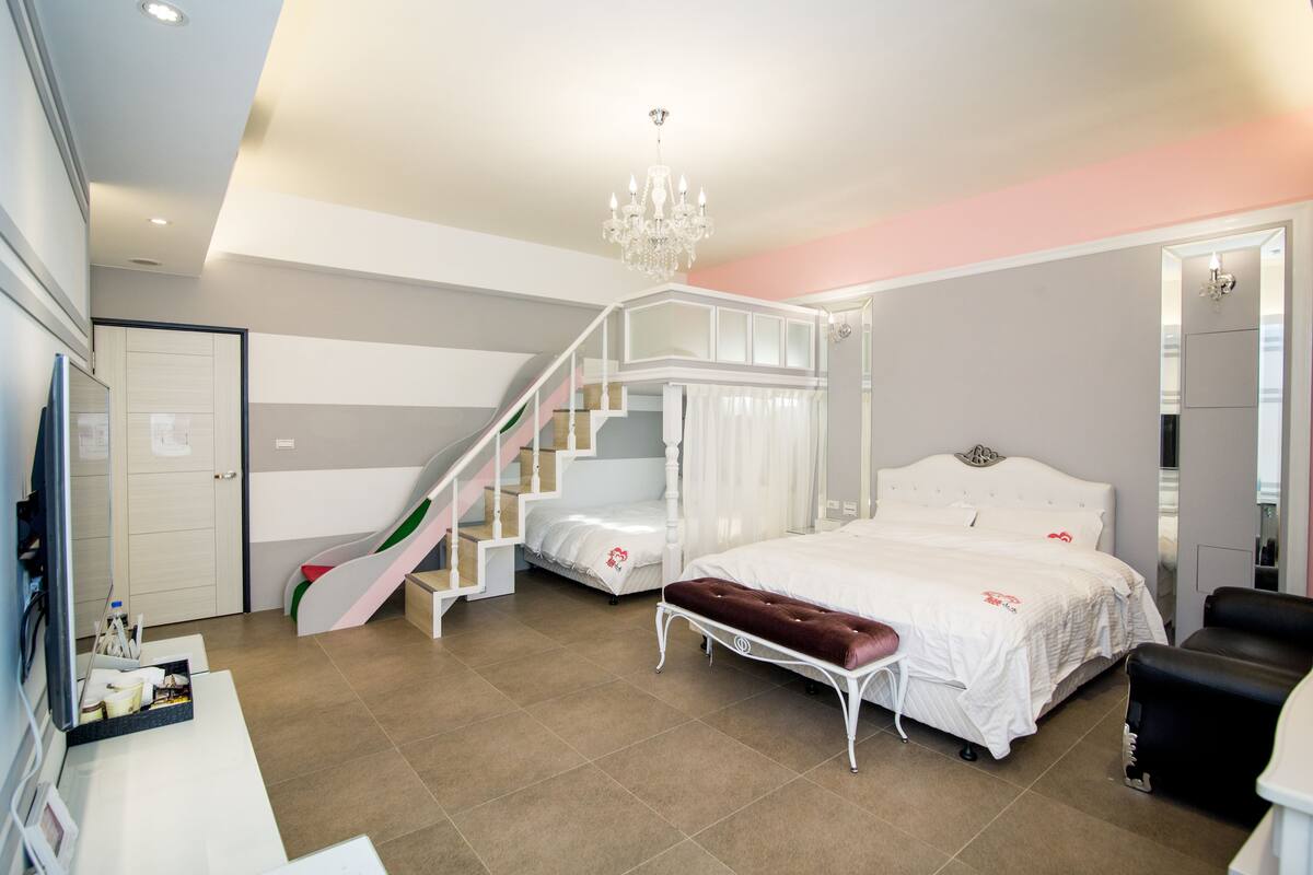 A bedroom with a bed, a bench, a staircase, and a chandelier.