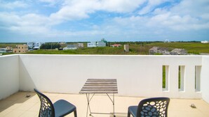 A balcony with a table and two chairs, overlooking a residential area with houses and greenery. - Ai Lian Shan Shui Homestay (Magong)