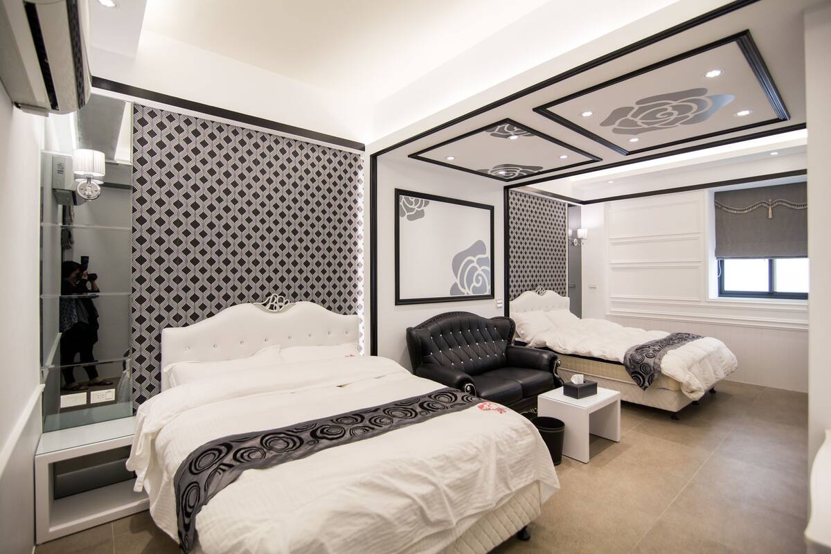 A modern bedroom with a large bed, a black leather chair, and a small bedside table.