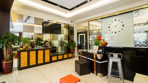 A modern hotel lobby with a reception desk, seating area, and decorative plants. - Ai Lian Shan Shui Homestay (Magong)