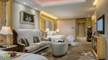 Habitación de hotel con sofá, dos camas, una mesita redonda y televisión.