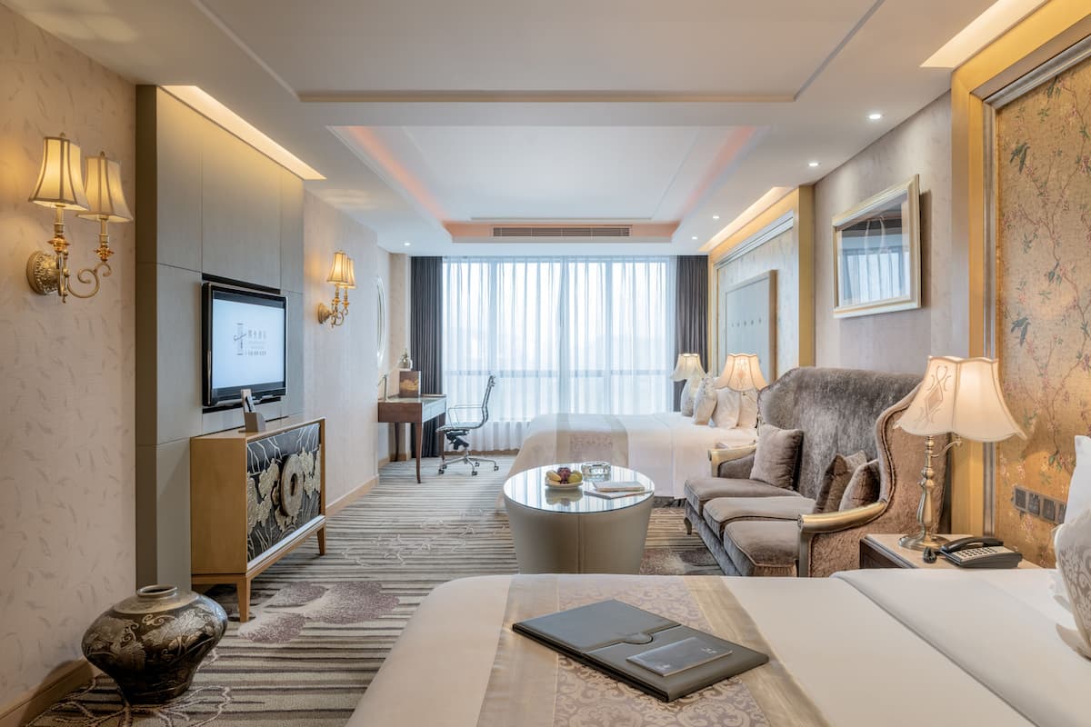 Ett hotellrum med en säng, en soffa, ett soffbord, en tv och ett skrivbord.