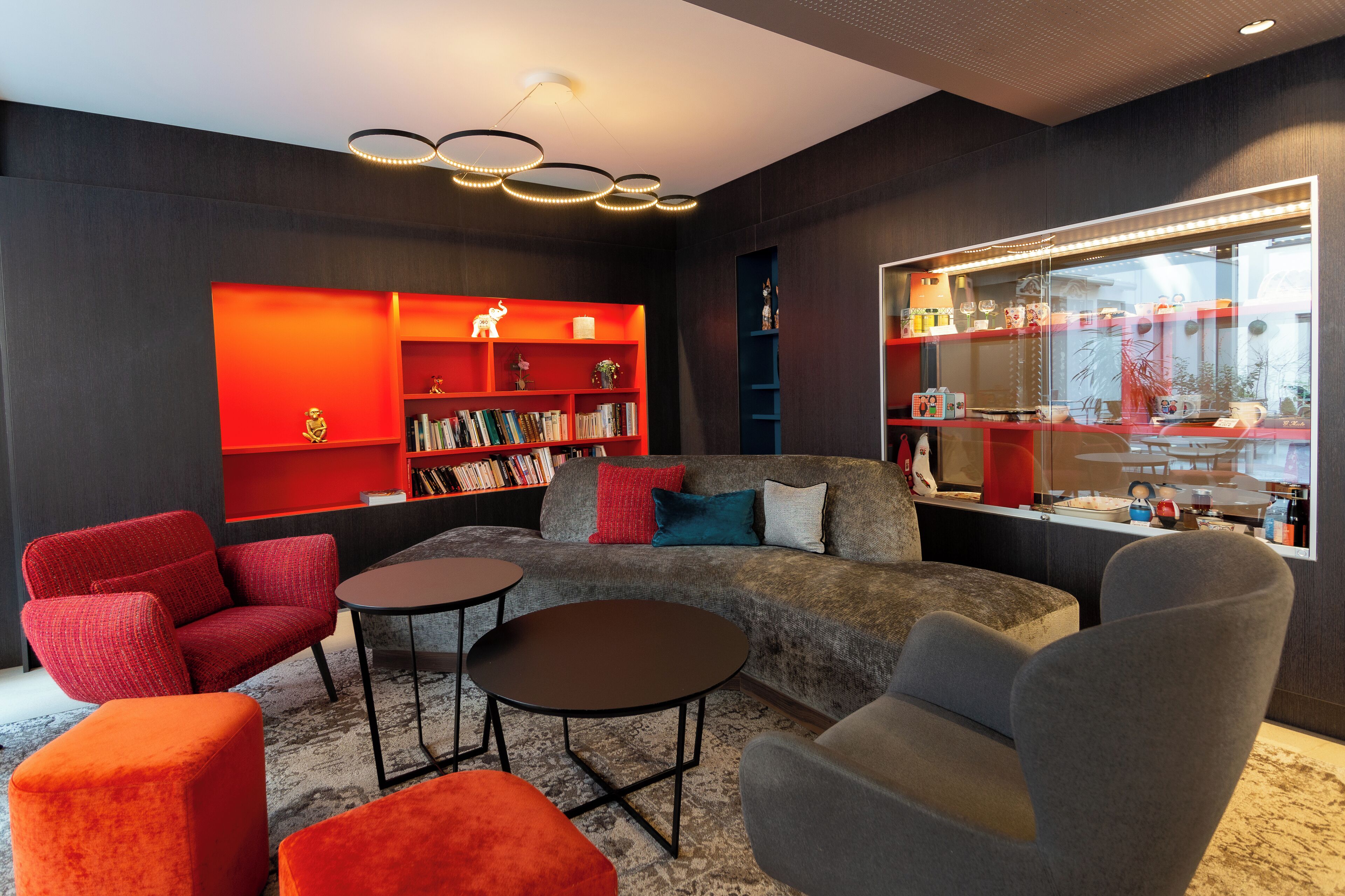 A modern living room with a sofa, two armchairs, a coffee table, and a bookshelf.
