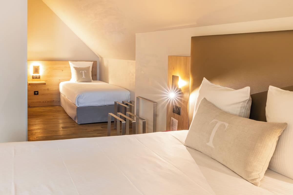A hotel room with a large bed, a wooden headboard, and a nightstand with a lamp.