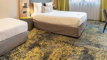 Una habitación de hotel con cama, mesita de noche, silla y ventana con cortinas.
