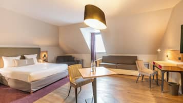 Una habitación de hotel con cama, escritorio, silla, sofá y mesa de comedor.