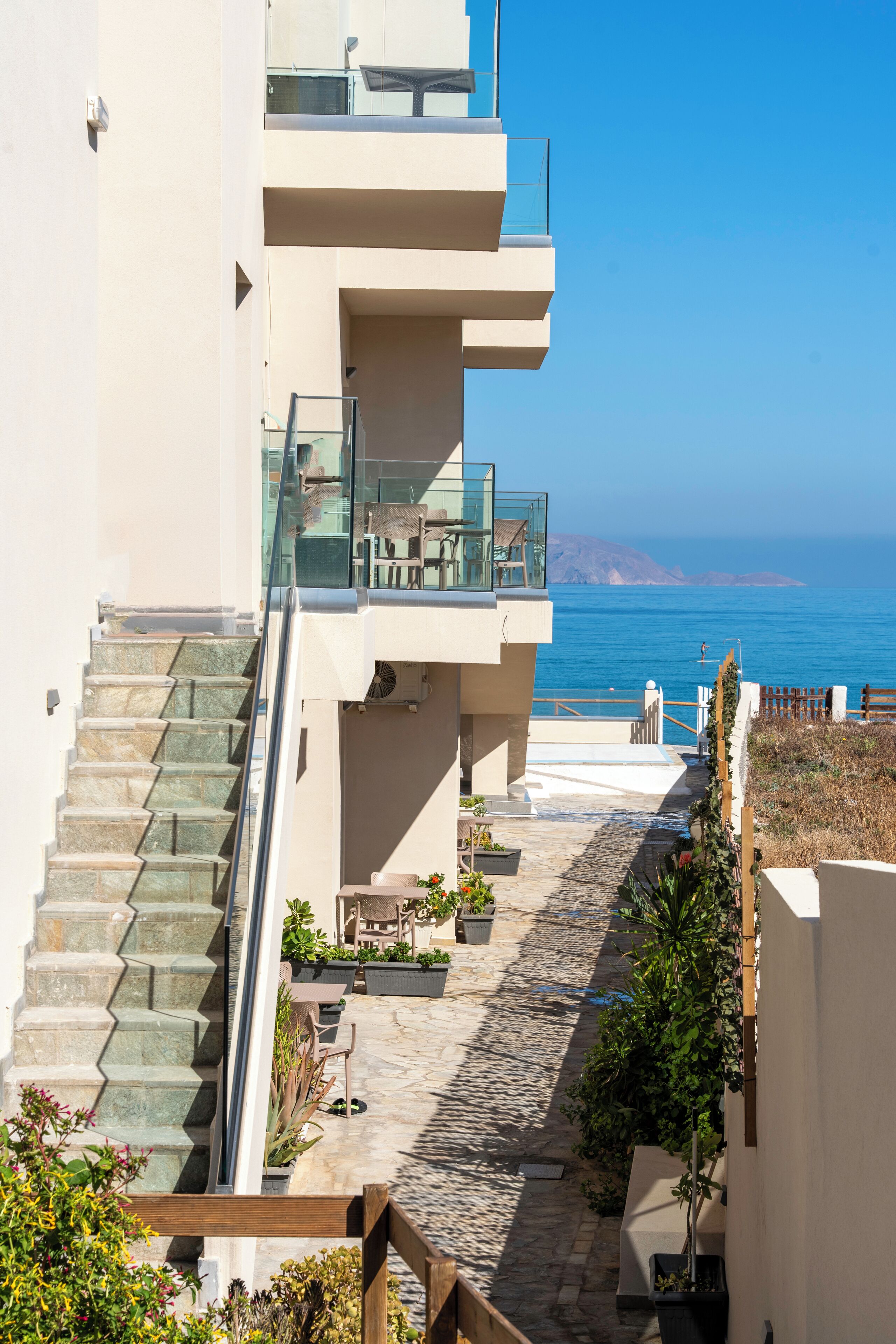A modern building with a staircase leading to a balcony overlooking a coastal view.