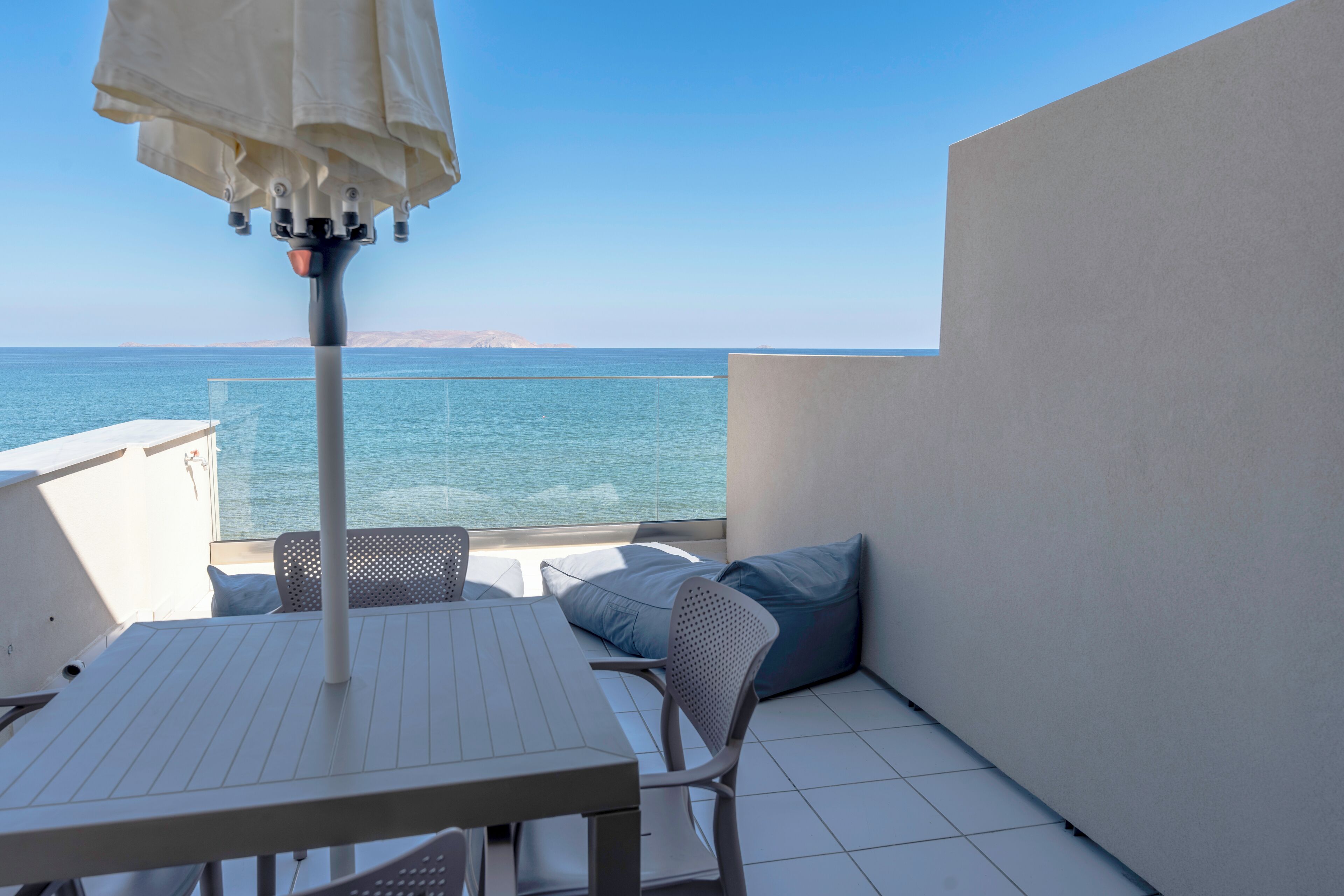 A balcony with a table and chairs, overlooking a body of water.