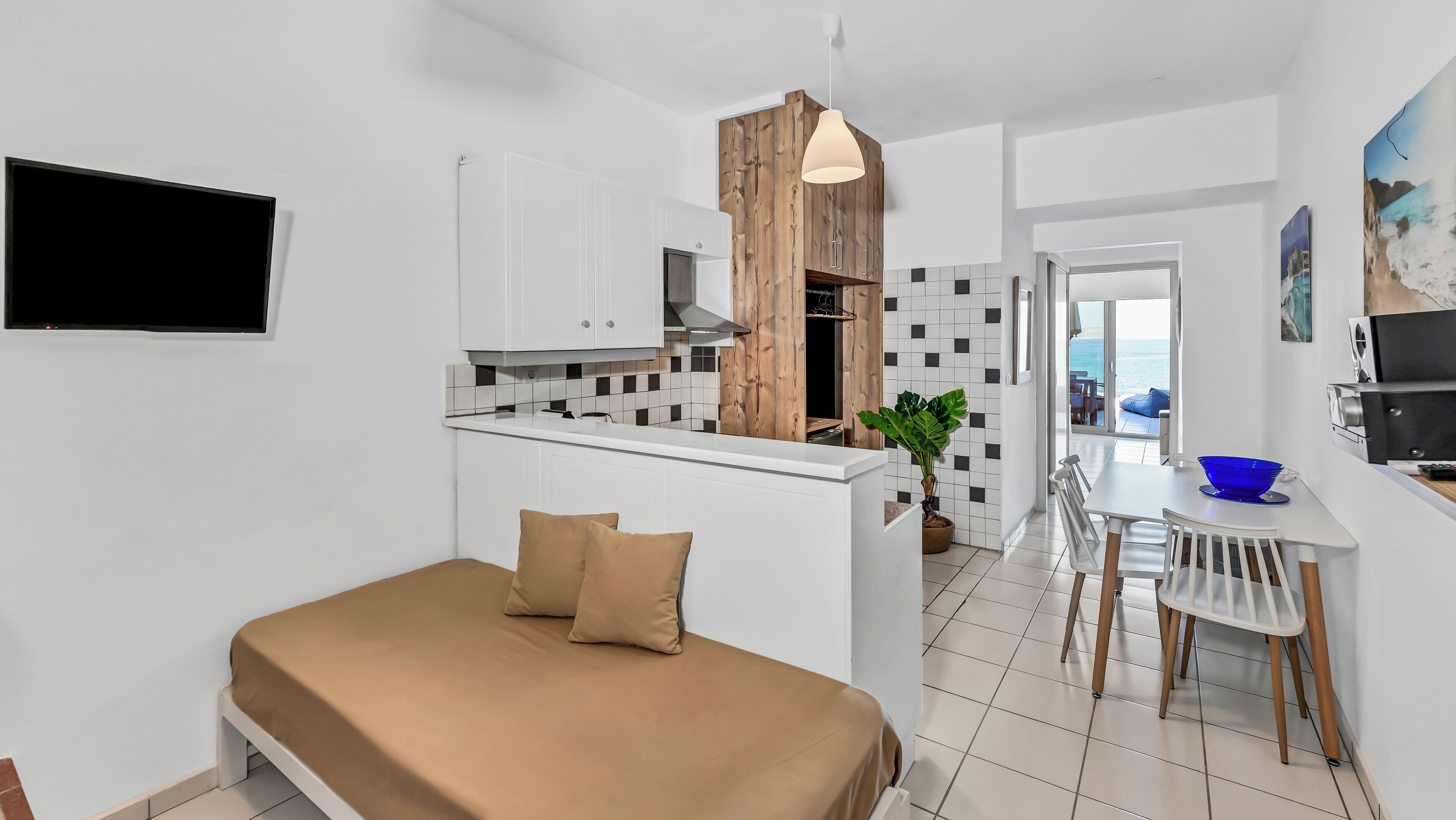 Ein kompaktes, modernes Apartment mit Küchenzeile, Essbereich und Bett.