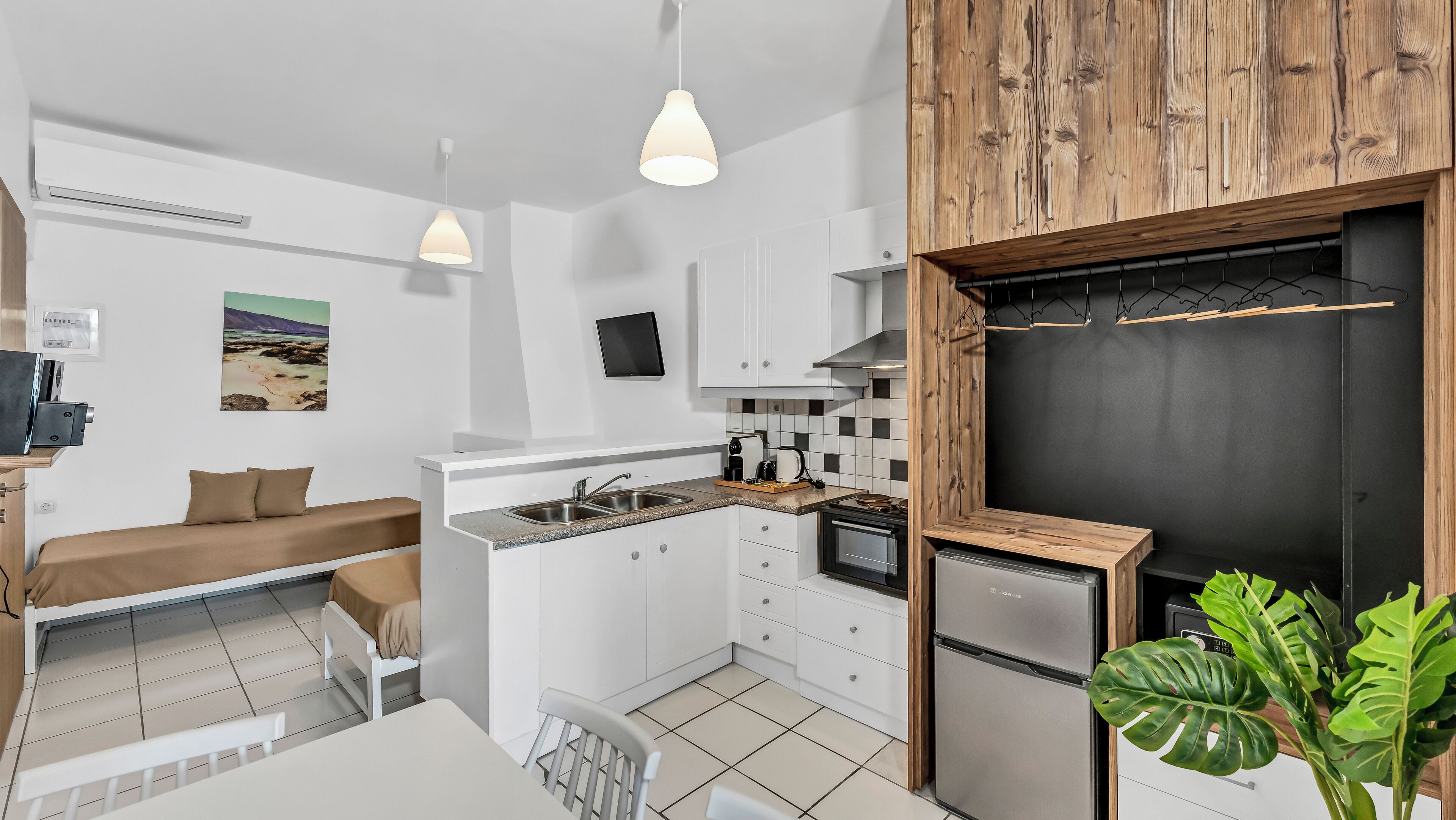A compact kitchen with white cabinets, a built-in oven, and a black backsplash.