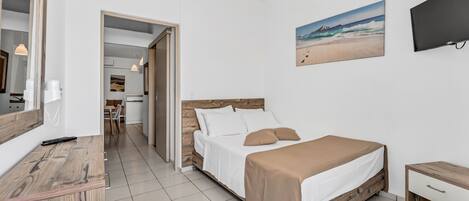 A bedroom with a bed, bedside table, and a painting of a beach scene.