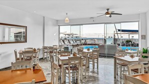 A restaurant with a pool view, white walls, and wooden furniture. - Almare Beach Hotel (Hersonissos)