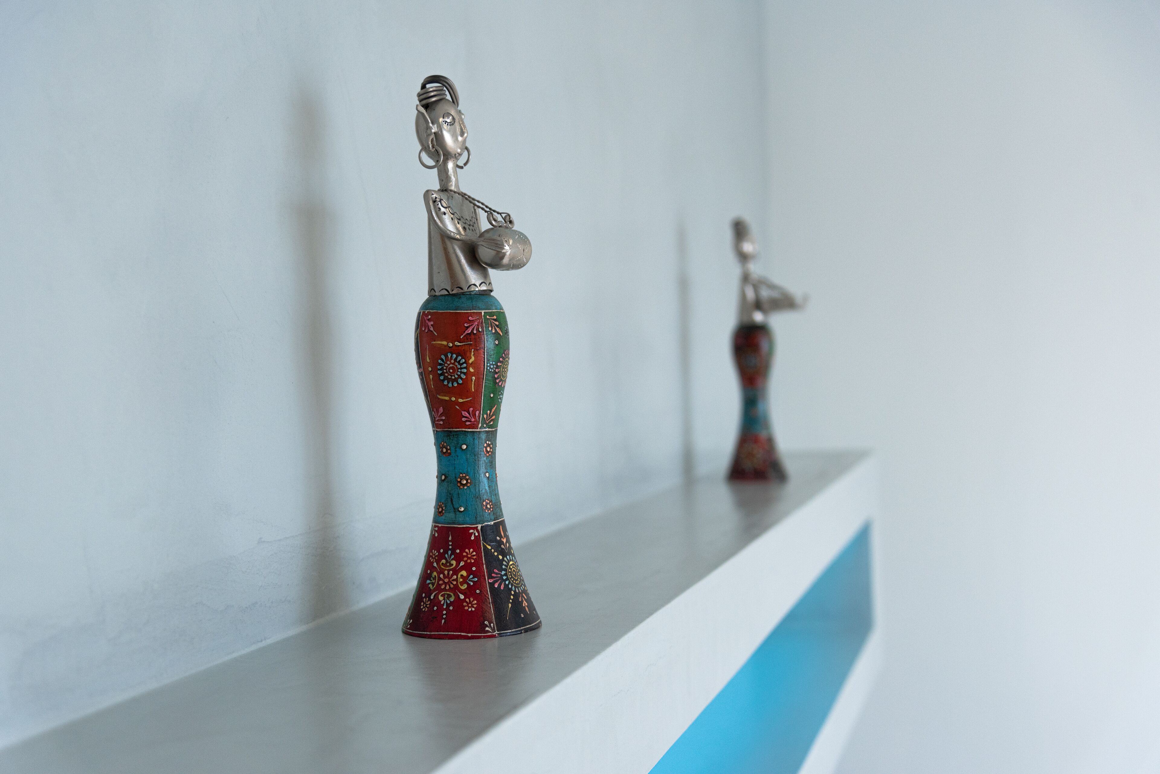 Two decorative figurines on a shelf against a plain wall.