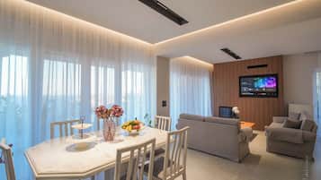 Un salon moderne comprenant un coin repas, un téléviseur à écran plat fixé au mur et un canapé.