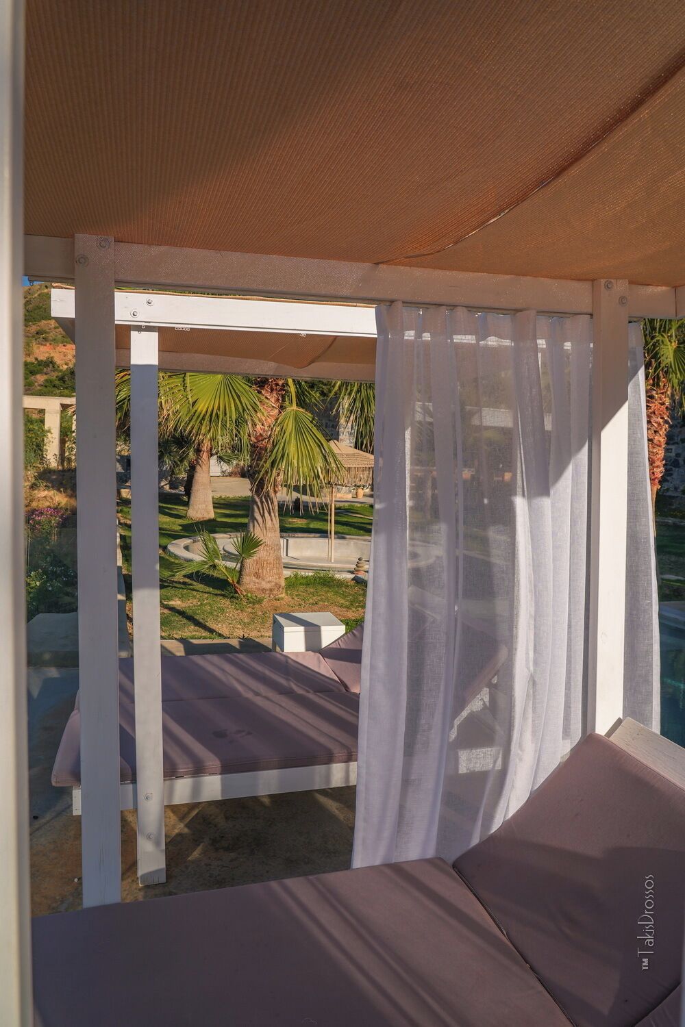 A covered outdoor seating area with a view of a landscaped garden.