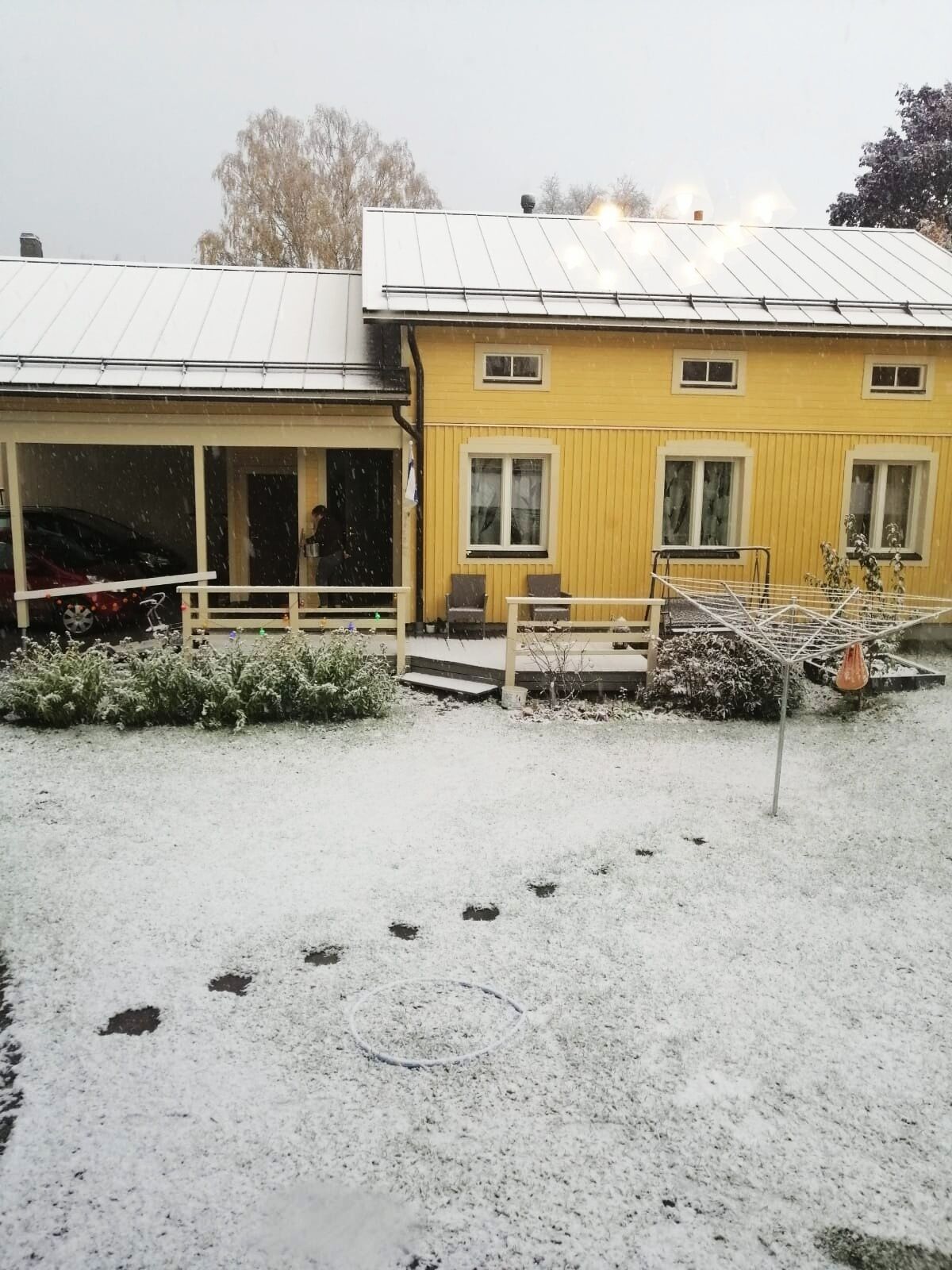 Un edificio de dos pisos con un espacio al aire libre cubierto y suelo cubierto de nieve.