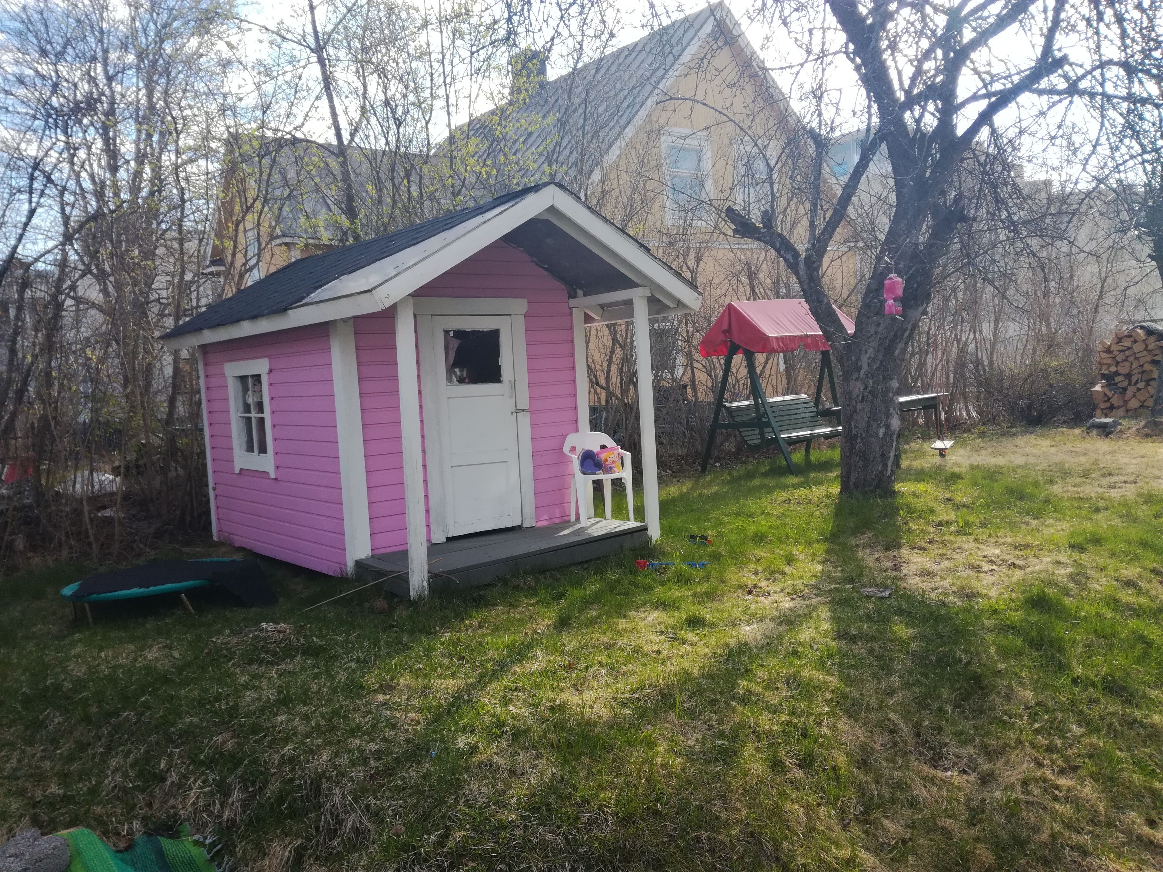 A small pink house with a porch and a swing.