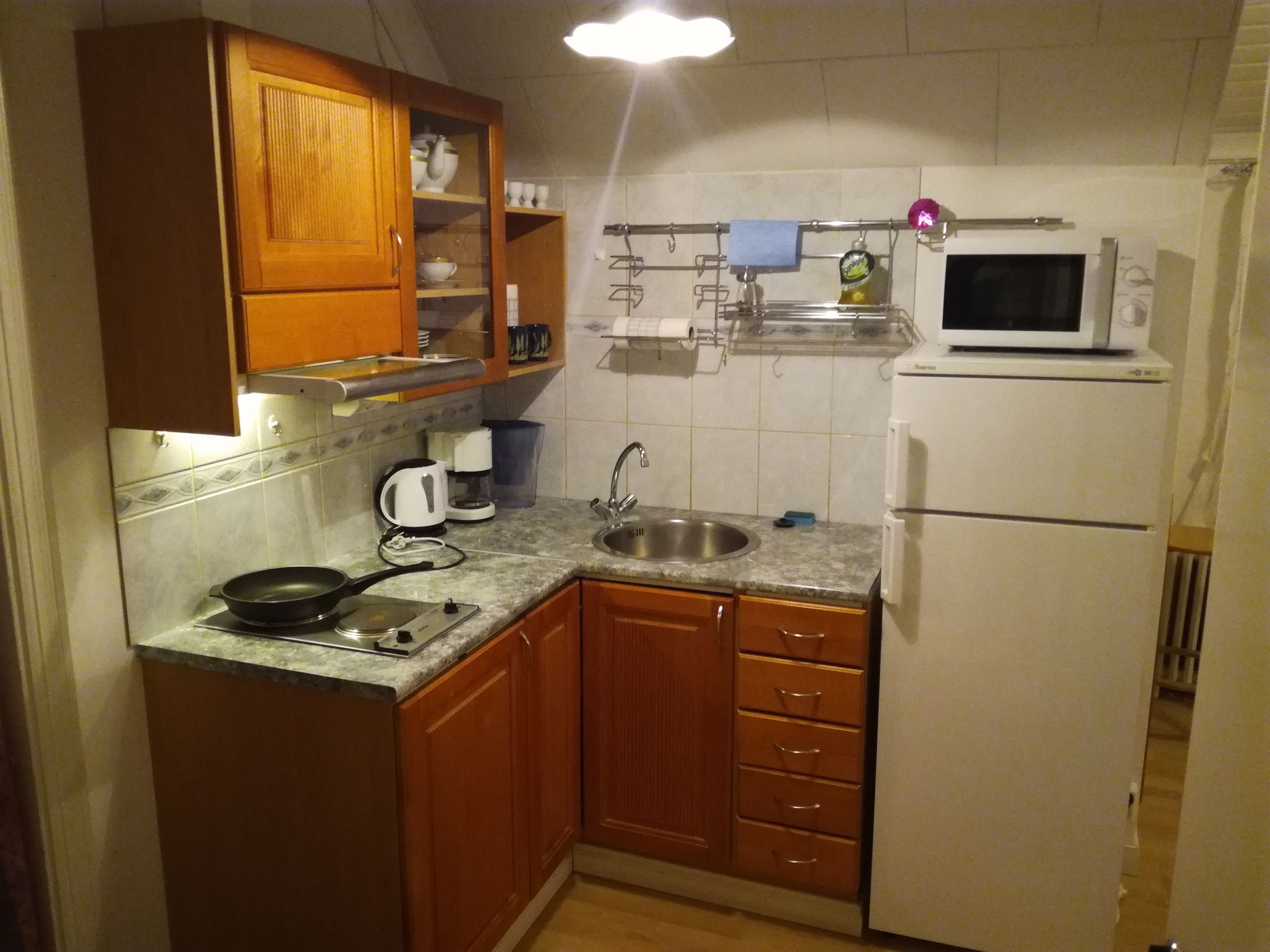 Una cocina compacta con armarios de madera, un fregadero, una estufa y un microondas.