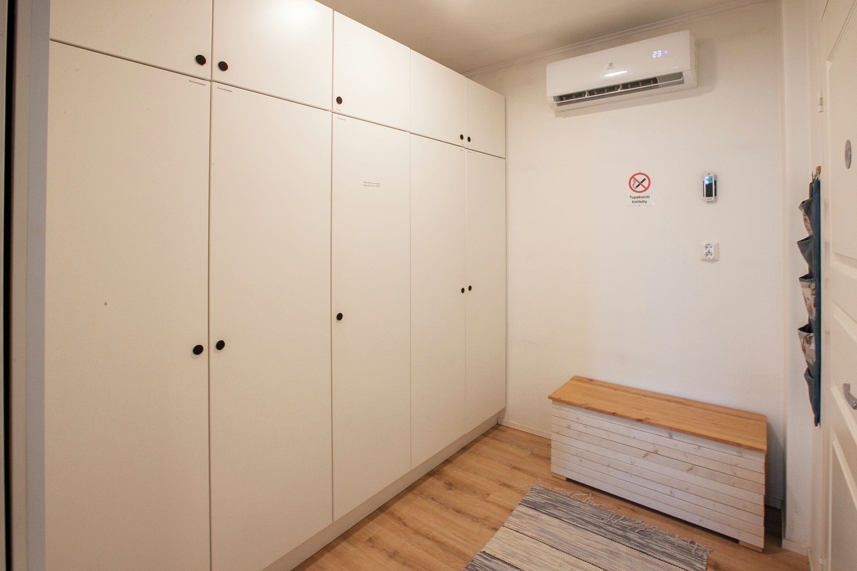 A room with a wardrobe, a bench, and a wall-mounted air conditioner.