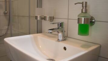 A bathroom with a white sink, a chrome faucet, and a green soap dispenser mounted on the wall.