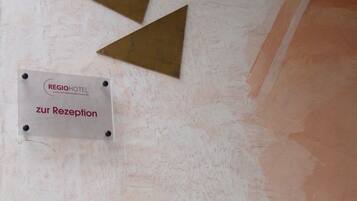 A sign for the reception area of a hotel, with four triangular plaques above it.