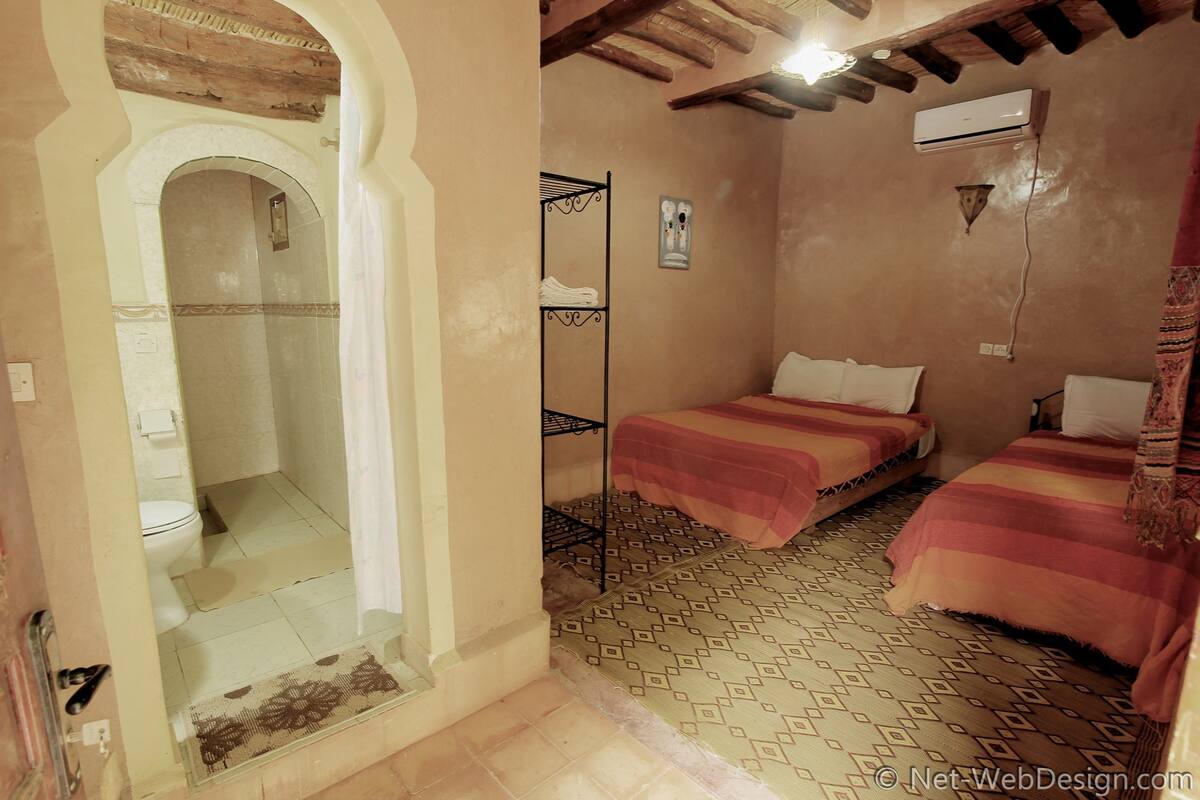 Een kamer met twee bedden, een douche en een kleine badkamer.