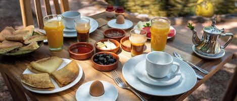 A breakfast table with toast, eggs, fruit, and beverages.