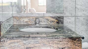 A bathroom with a marble sink, a glass shower enclosure, and a large mirror.