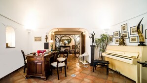 A dining area with a piano, chairs, and a table with a decorative item. - Maison Fernanda (Massa Lubrense)