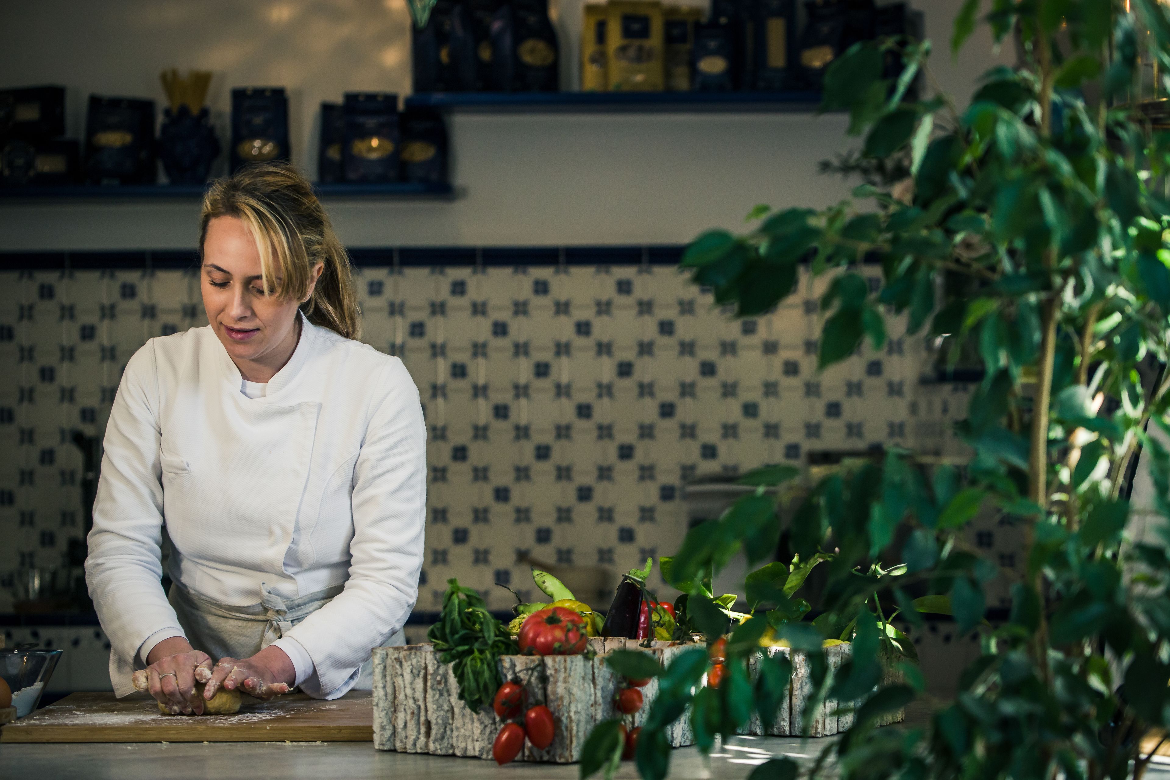 Un chef preparando comida en una cocina con un salpicadero decorado y diversos vegetales en la encimera.