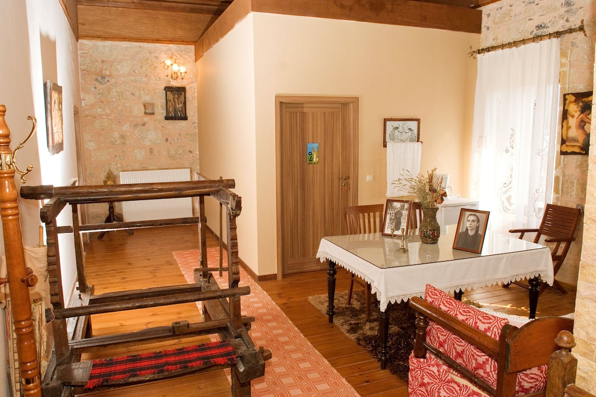 Une table à manger traditionnelle en bois, avec des chaises, un banc en bois et un tapis à motifs.