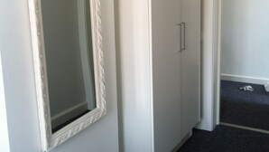 Um quarto com um espelho grande, um guarda-roupa e uma porta.