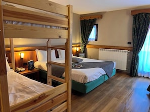A room with bunk beds, a bedside table with a lamp, and a window with curtains. - Hotel de Champoluc (Ayas)