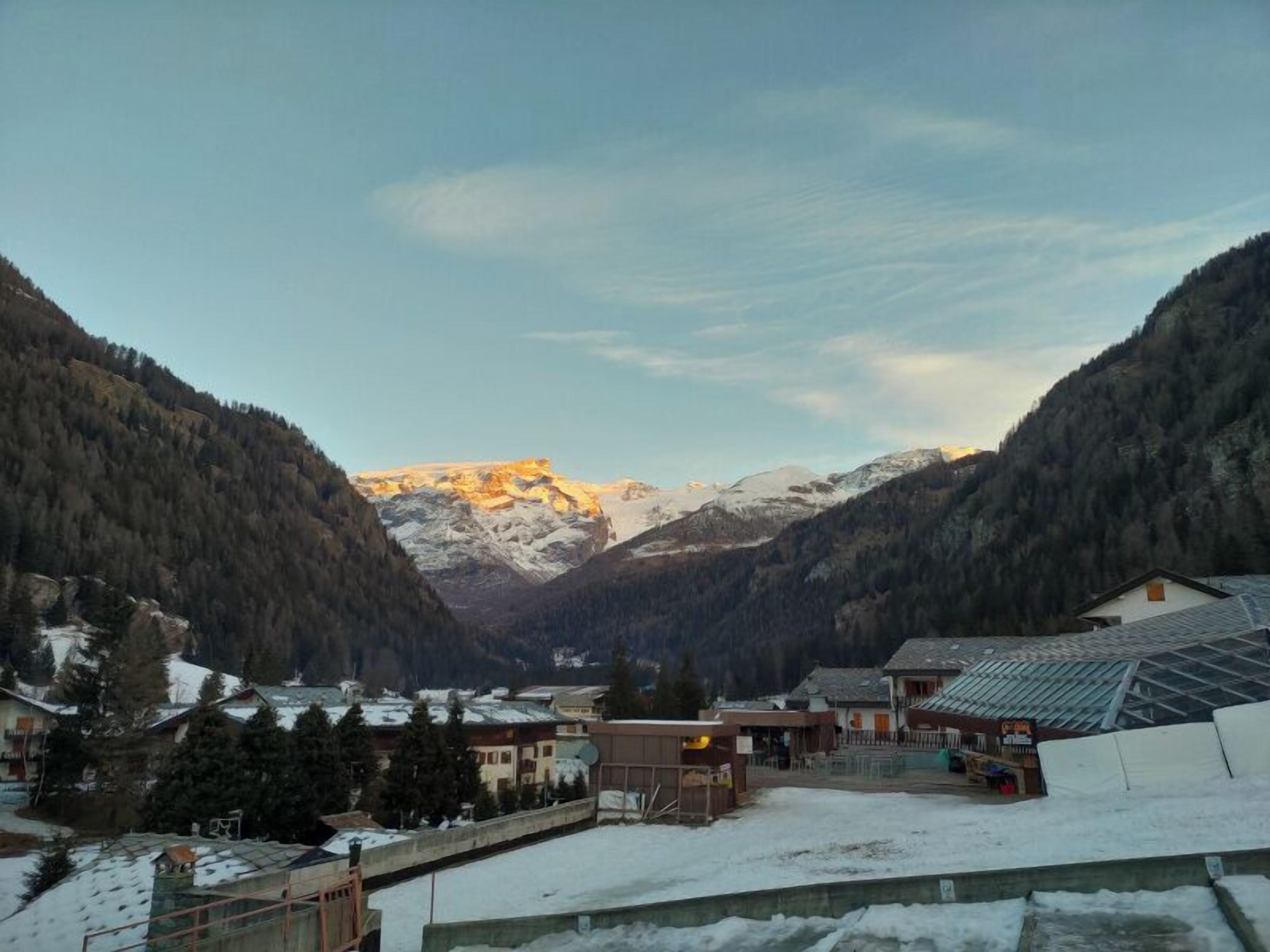 A mountainous village with buildings and a snow-covered landscape.