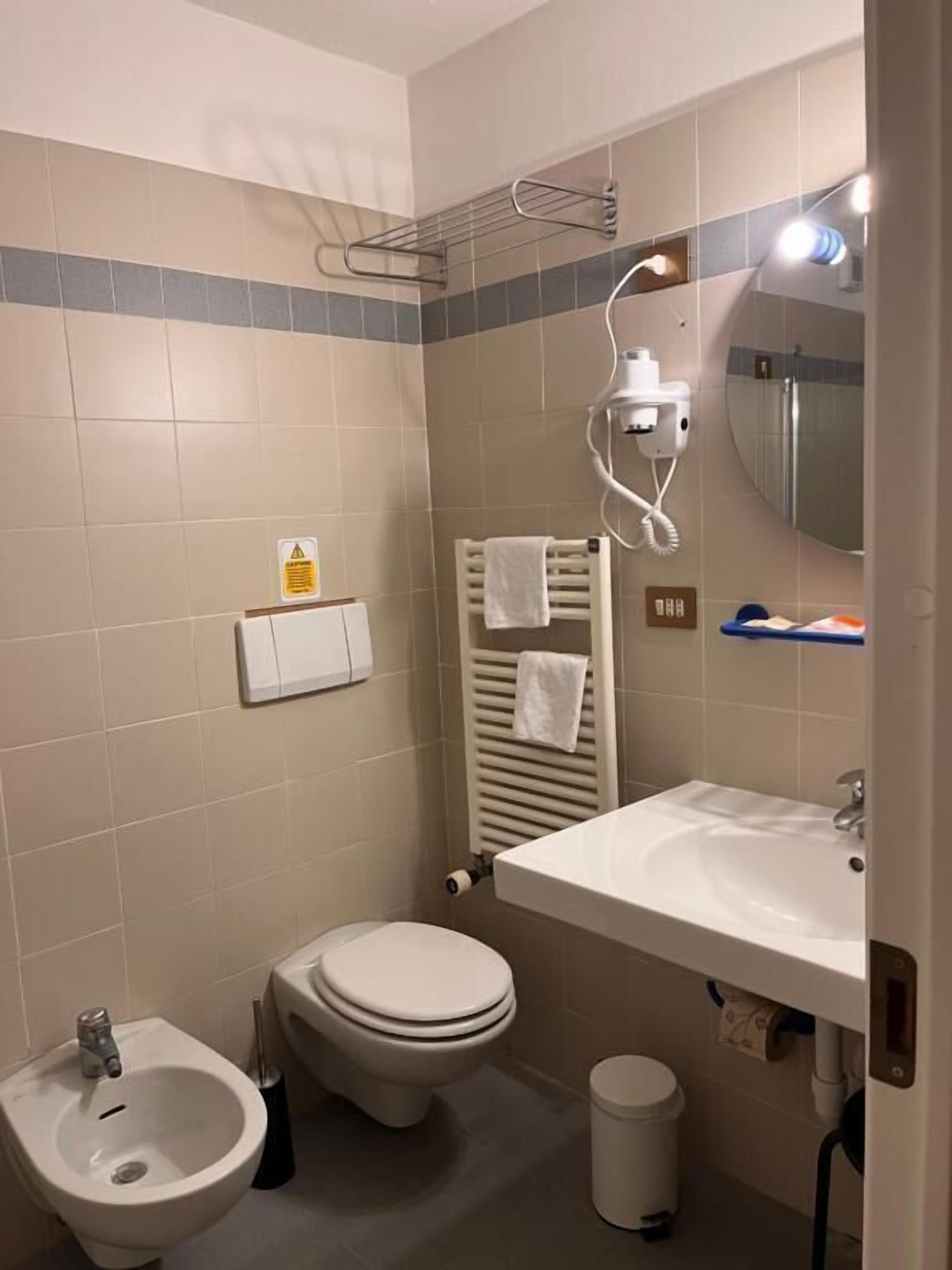Un baño con bidé, inodoro, lavamanos y toallero.