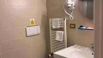 Un baño con bidé, inodoro, lavamanos y toallero.