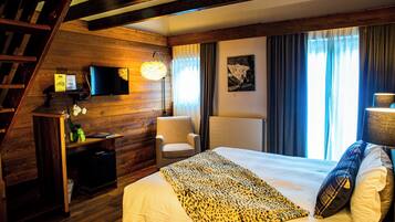 A hotel room with a wooden interior, a bed with a leopard print blanket, a chair, a desk with a television, and a staircase.