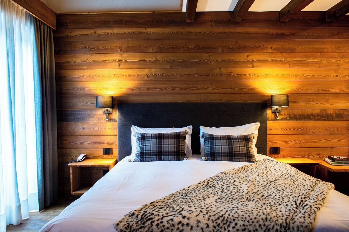 A hotel room with a wooden headboard, two bedside lamps, a telephone, and a leopard print throw blanket.