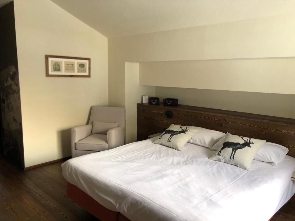 Ein Hotelzimmer mit einem großen Bett, einem Holzkopfstück und einem Sessel.