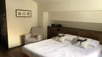 Ein Hotelzimmer mit einem großen Bett, einem Holzkopfstück und einem Sessel.