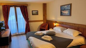 A hotel room with a bed, a desk, a chair, and a painting on the wall.