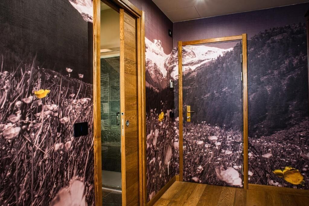 Une pièce avec une porte en bois et une peinture murale représentant un paysage montagneux.