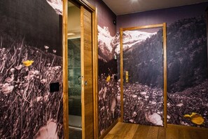 Una habitación con puerta de madera y un mural en la pared que muestra un paisaje montañoso.