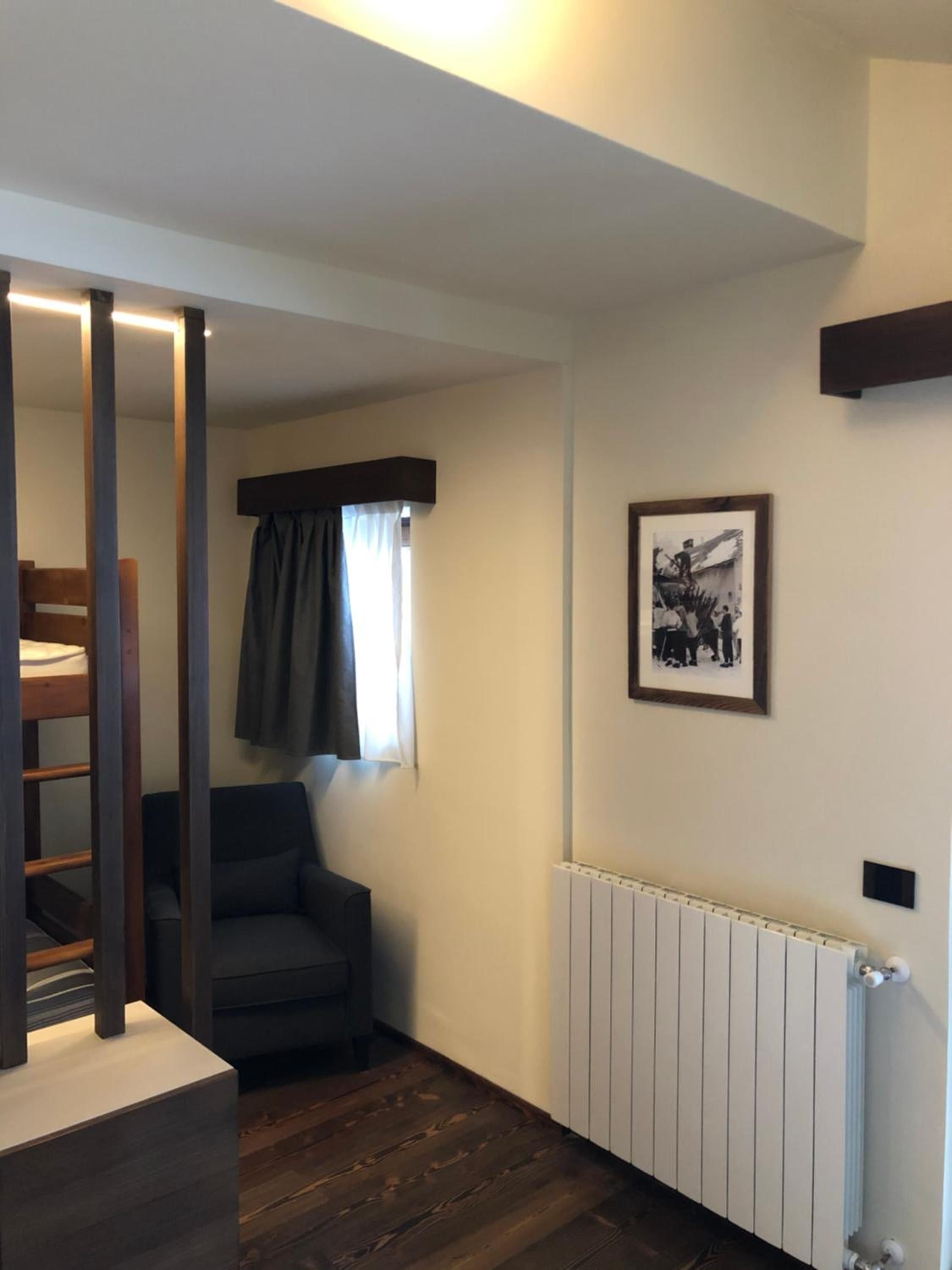 Una habitación con literas, una silla, un radiador y un cuadro en la pared.