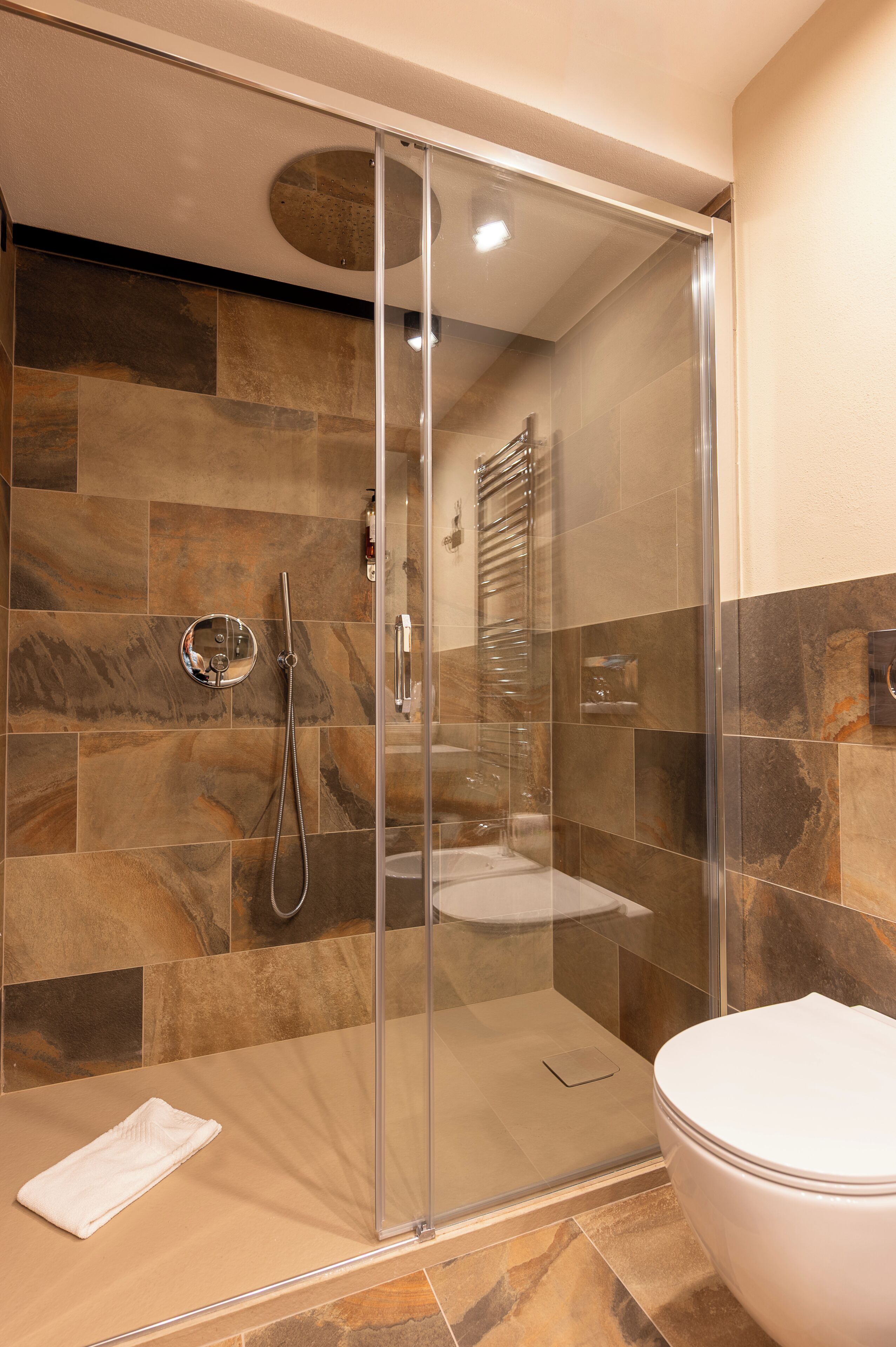 A modern bathroom with a glass-enclosed shower, a toilet, and a towel.