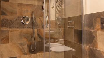 A modern bathroom with a glass-enclosed shower, a toilet, and a towel.