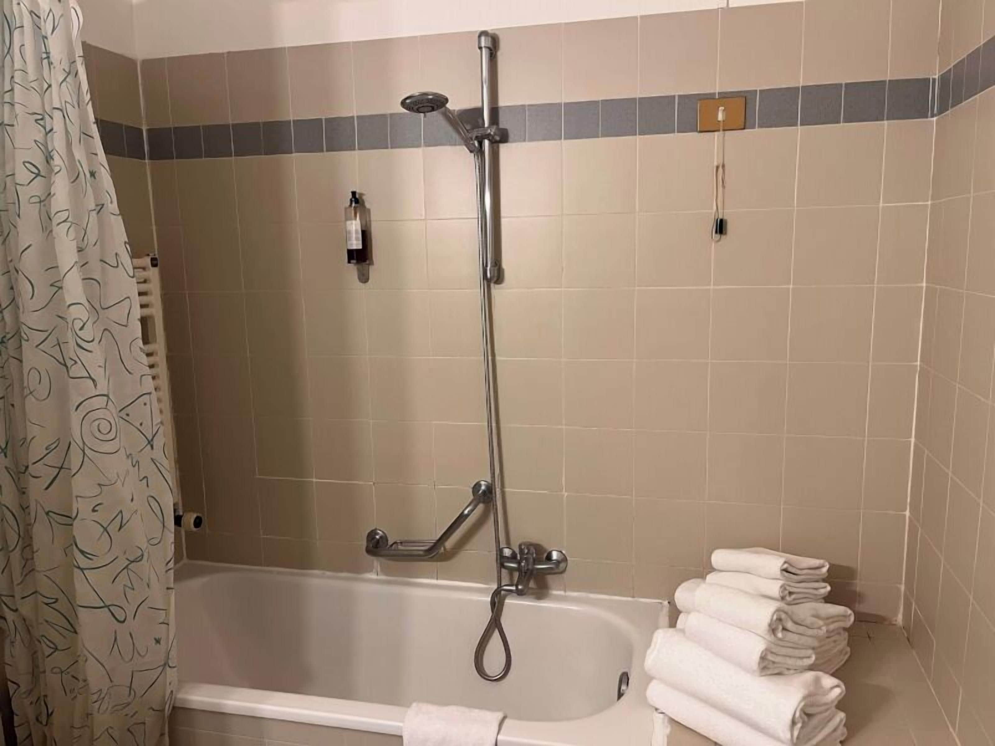 Un baño con bañera, ducha y toallero con toallas.